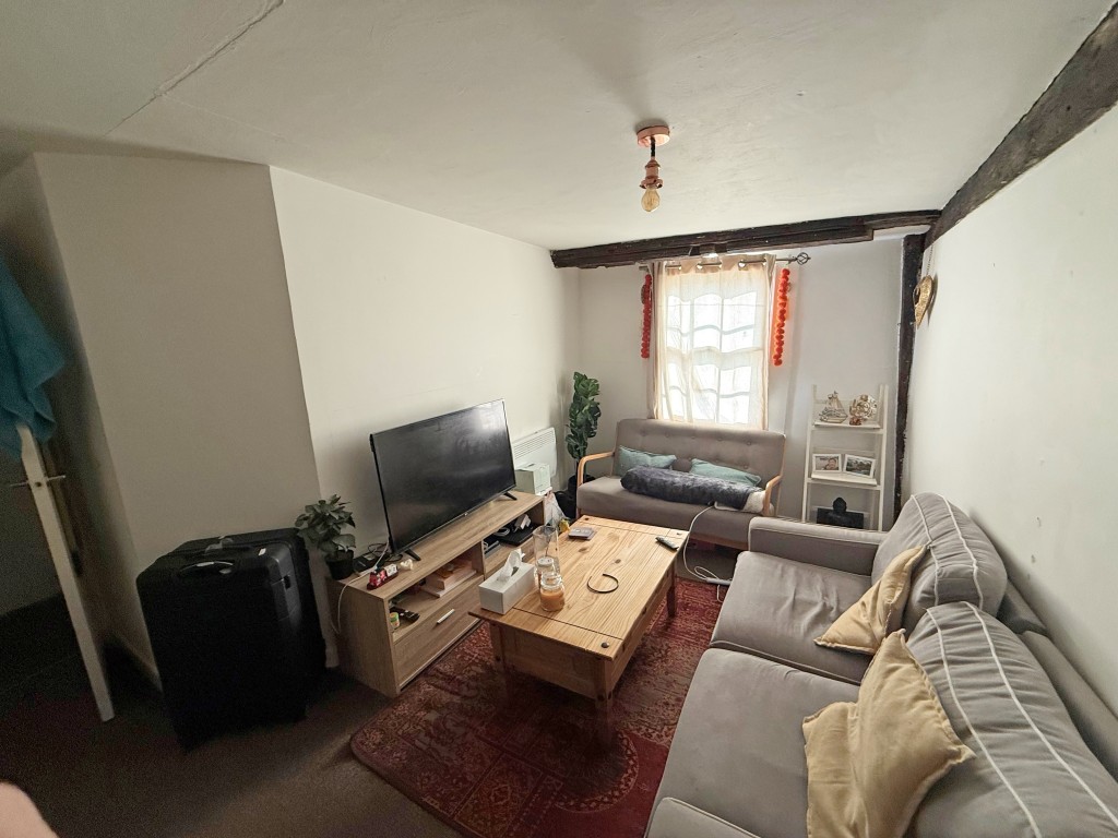 Lot: 134 - FREEHOLD RESIDENTIAL INVESTMENT PROPERTY ARRANGED AS FIVE FLATS - Upstairs carpeted flat lounge with window and exposed beams